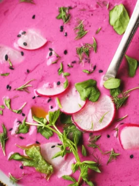 A bowl of vibrant Kefir Beet Gazpacho garnished with fresh herbs.