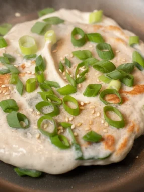 Delicious Kefir Black Sesame Pancakes served with syrup and garnished with sesame seeds.