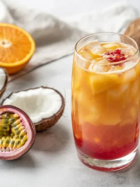 Tropical Sunset Mango-Passionfruit Coconut Water Kefir in a glass with fresh fruit.